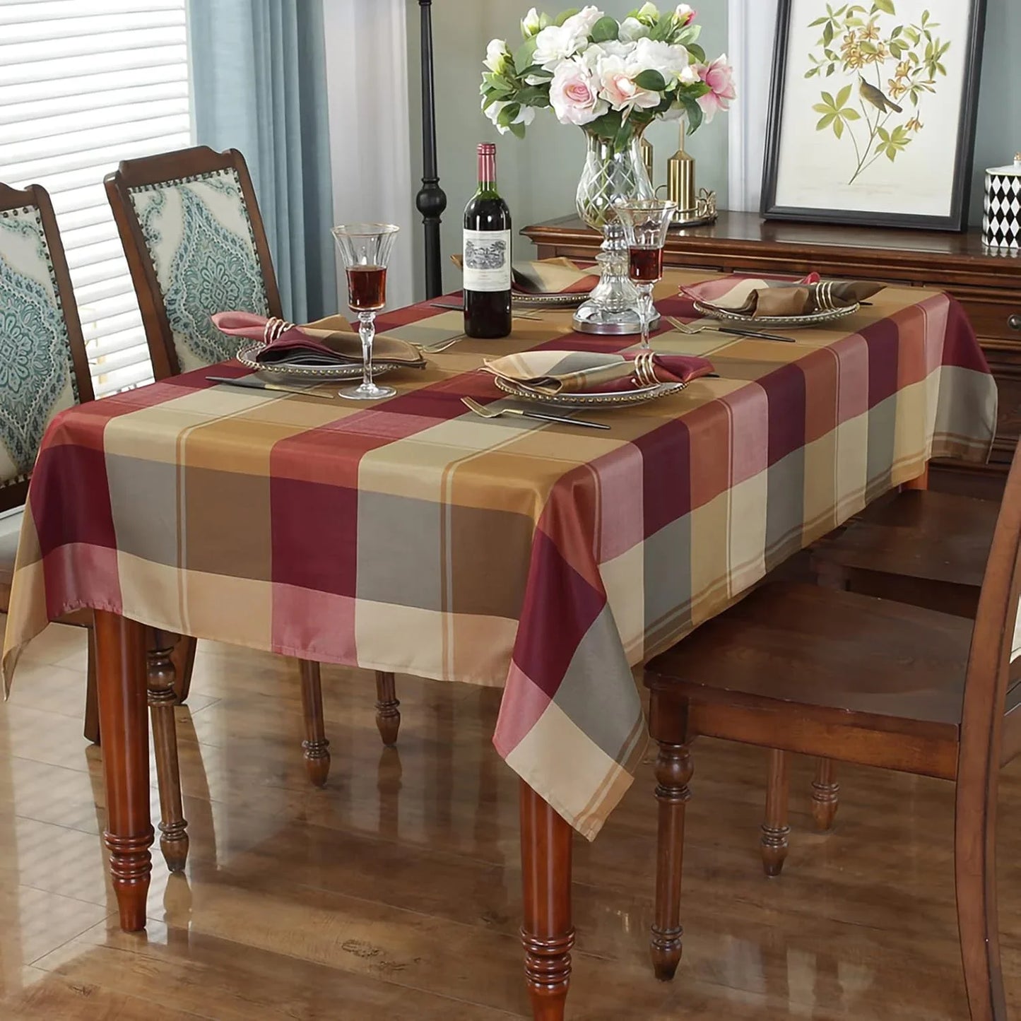 Dining table set with a checkered tablecloth, wine glasses, and a vase of flowers.