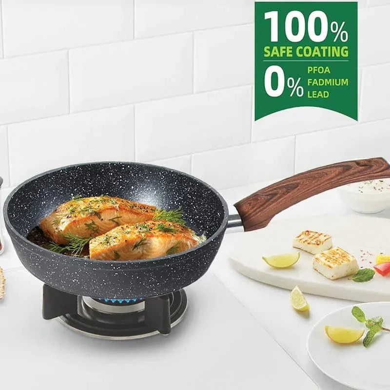 Granite black nonstick frying pan with wooden handle cooking salmon on gas stove, white kitchen background