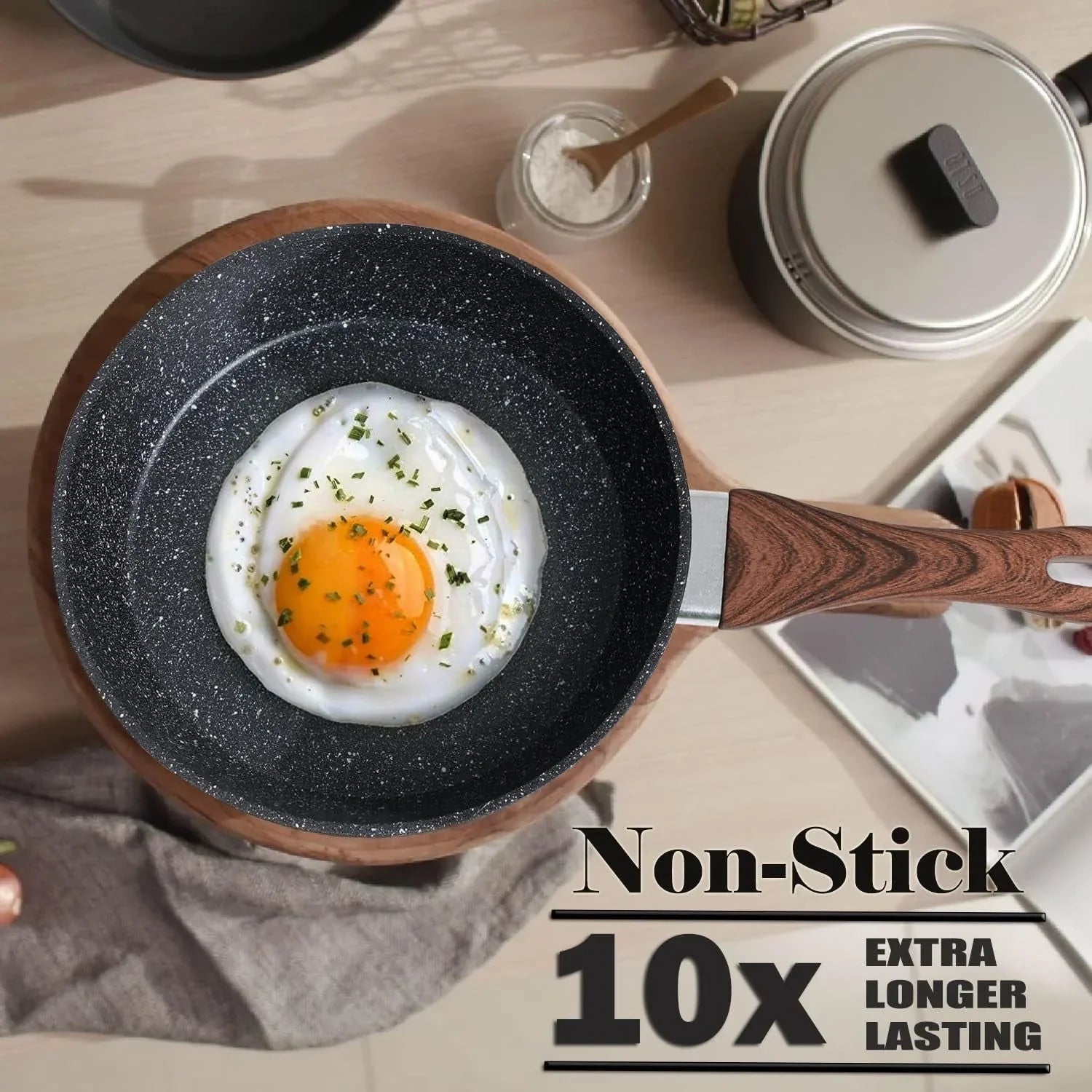 Granite black non-stick frying pan with wooden handle cooking a fried egg seasoned with herbs on a wooden surface