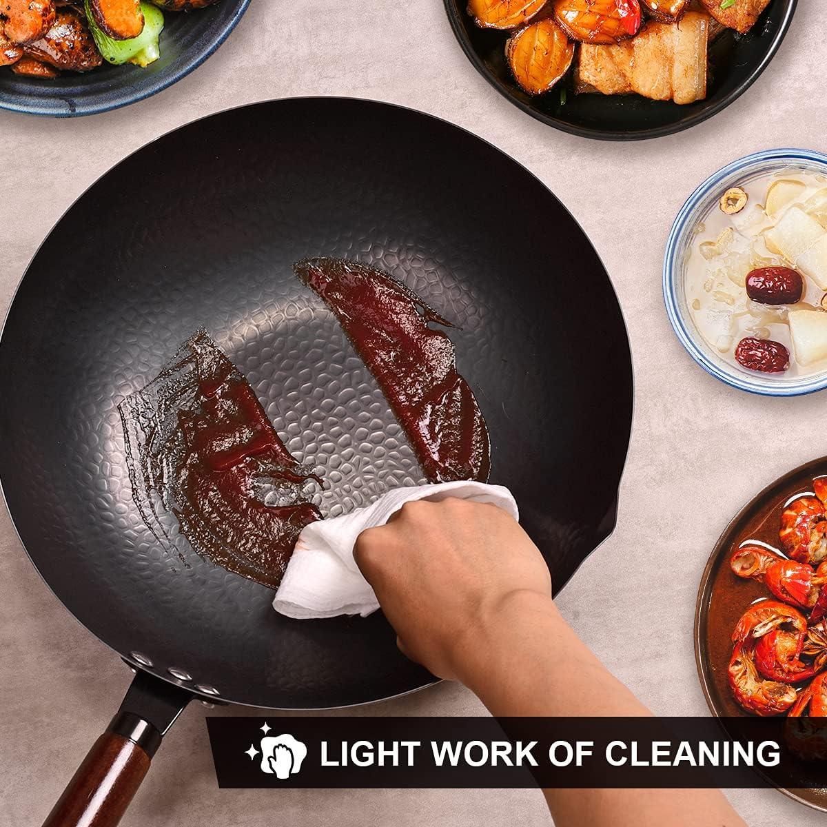 Hand wiping a black hammered wok pan with a cloth, surrounded by plates of cooked food