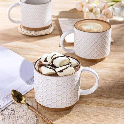 Set of textured off-white ceramic coffee mugs on wooden table with hot chocolate and latte art