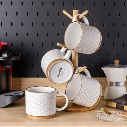 Set of four textured off-white ceramic coffee mugs with wooden coaster and stand on wooden counter