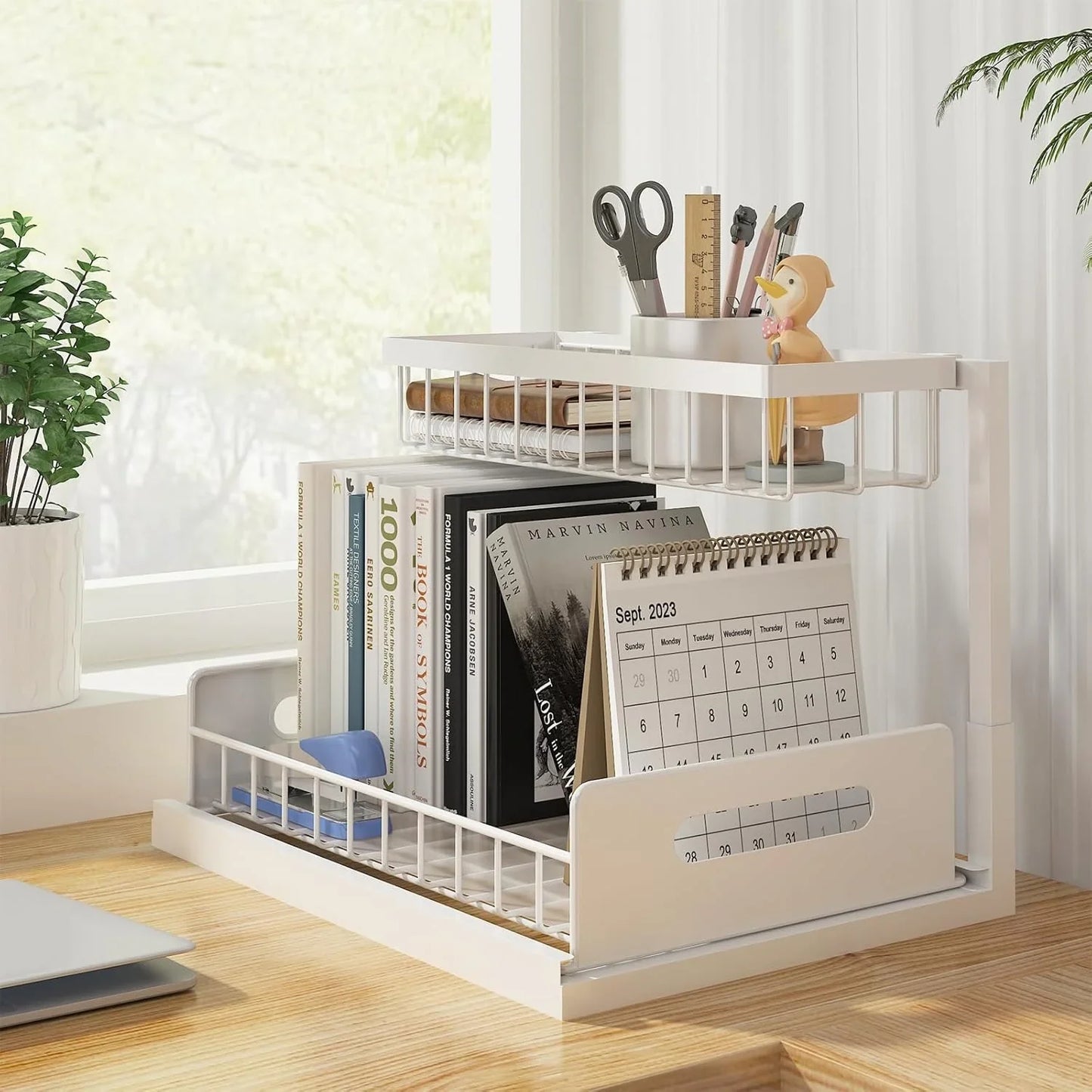 Two-tier white metal desktop organizer with books, calendar, pen holder, and small decor on wooden desk