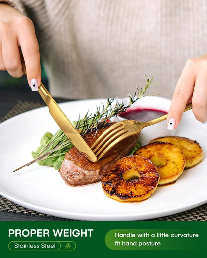 Gold stainless steel flatware cutting steak with grilled pineapple and sauce on white plate