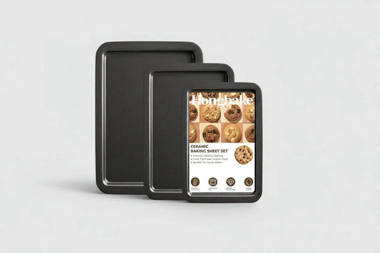 Three-piece black nonstick ceramic baking sheet set with packaging label featuring cookies
