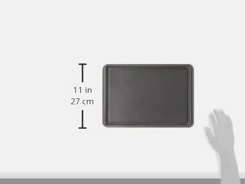 small nonstick carbon steel baking sheet, 11 inches long, with hand for size reference on white background