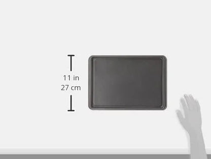 small nonstick carbon steel baking sheet, 11 inches long, with hand for size reference on white background