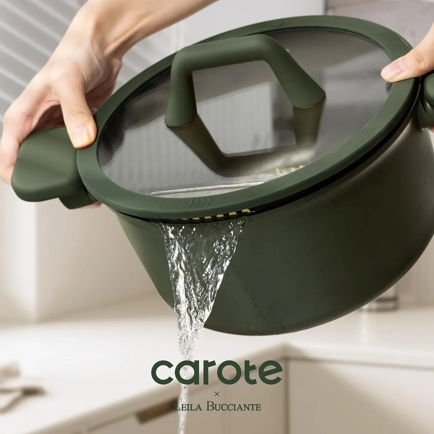 Green pot with glass lid draining water through built-in strainer in modern kitchen
