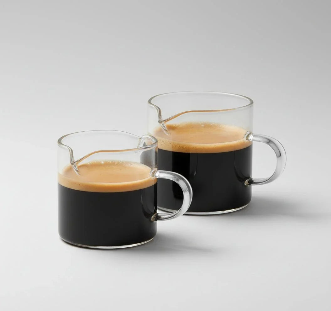 Set of two clear borosilicate glass 4 oz double spout espresso cups with handles filled with espresso