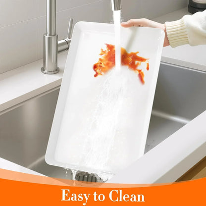 Person rinsing white rectangular plastic serving tray with red food stains under kitchen sink faucet