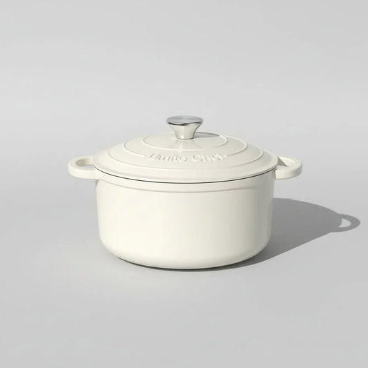 Cream white enameled cast iron Dutch oven with lid and stainless steel knob on light background