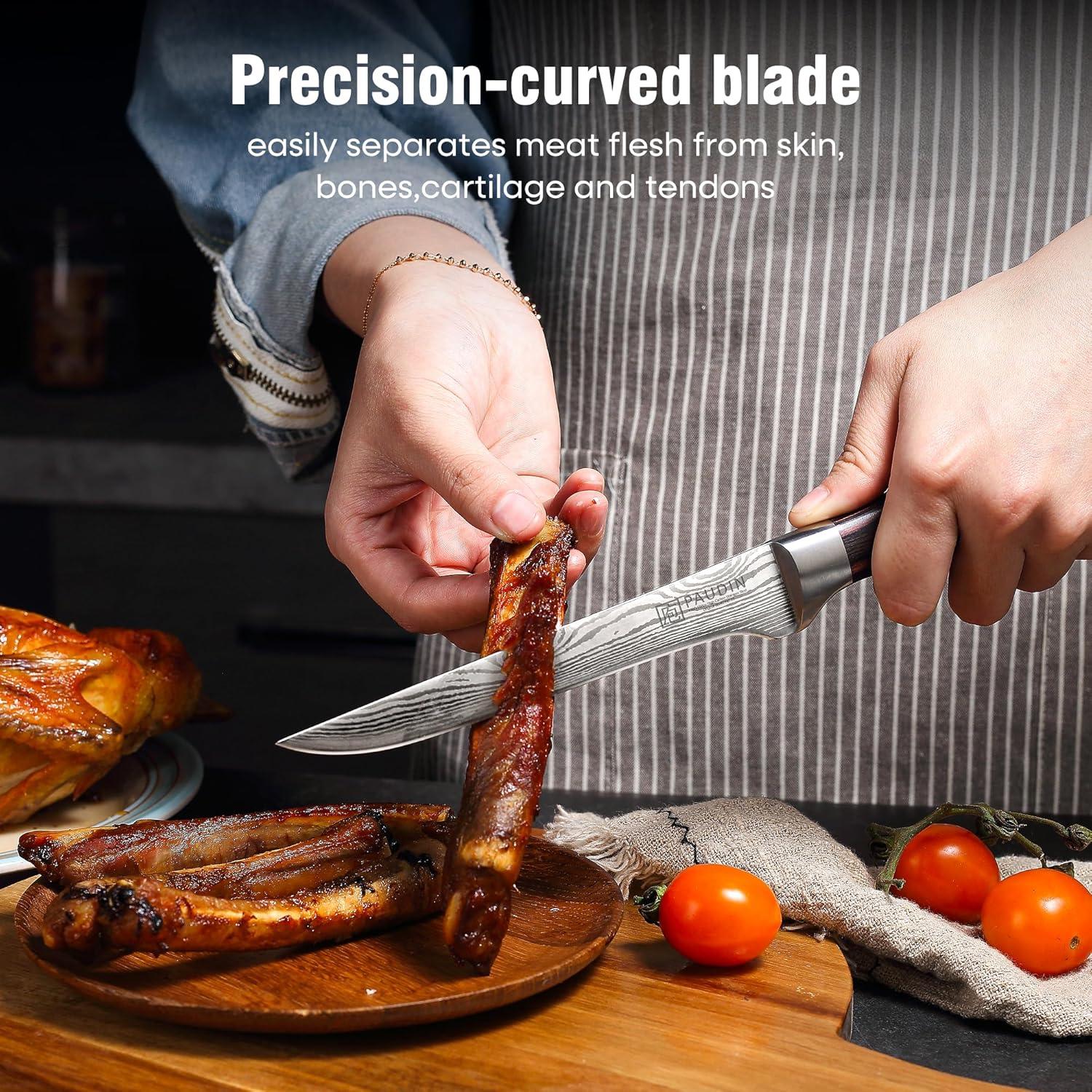 Hand holding a precision-curved boning knife removing meat from ribs on a wooden plate with tomatoes nearby