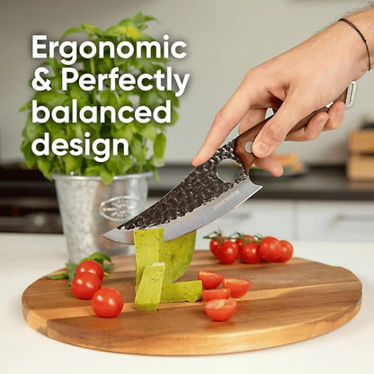 Hand holding a hammer-textured chef knife slicing cactus on wooden cutting board with cherry tomatoes