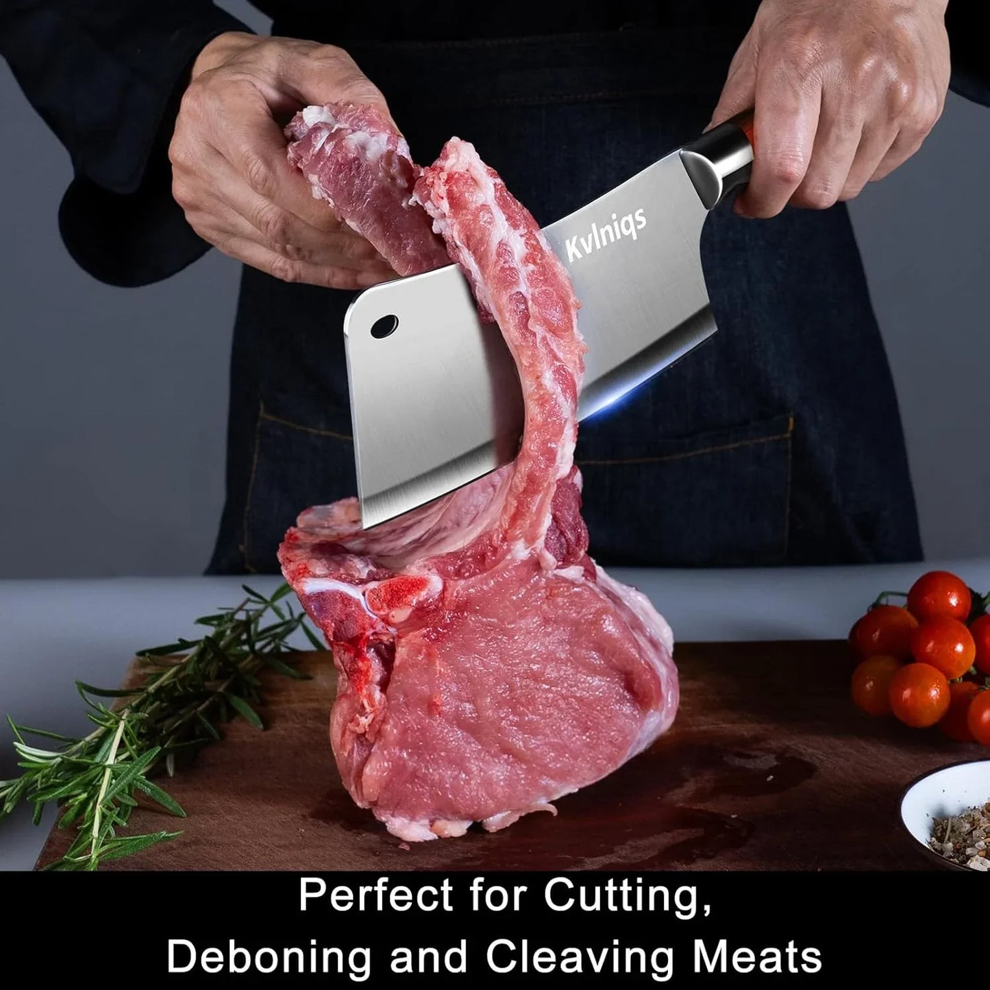 Hand using Kvlniqs meat cleaver to cut raw pork chop on wooden board with rosemary and cherry tomatoes