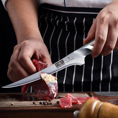 Hand holding Japanese 7-inch high carbon steel fillet knife slicing raw meat on wooden cutting board