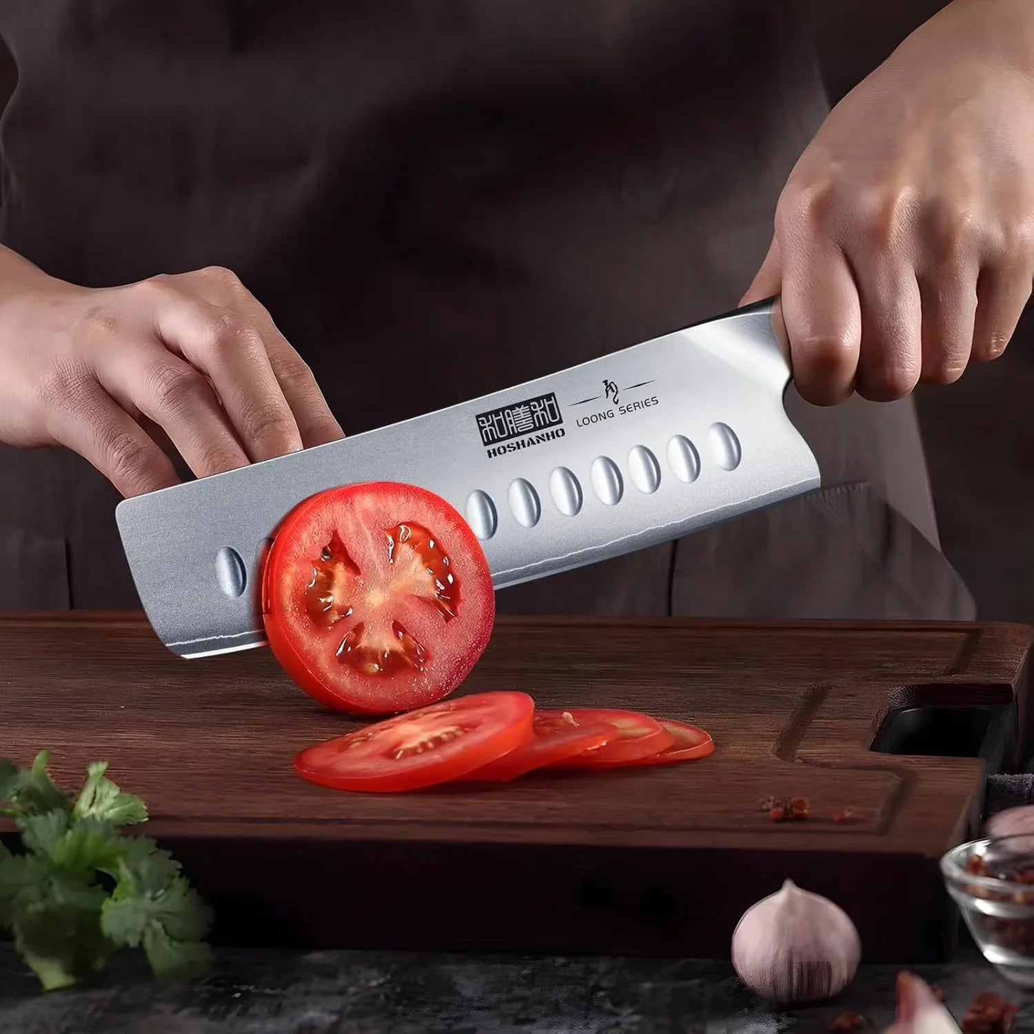 Hands slicing a fresh tomato with a HOSSHANHO Loong Series Japanese Nakiri knife on a wooden cutting board