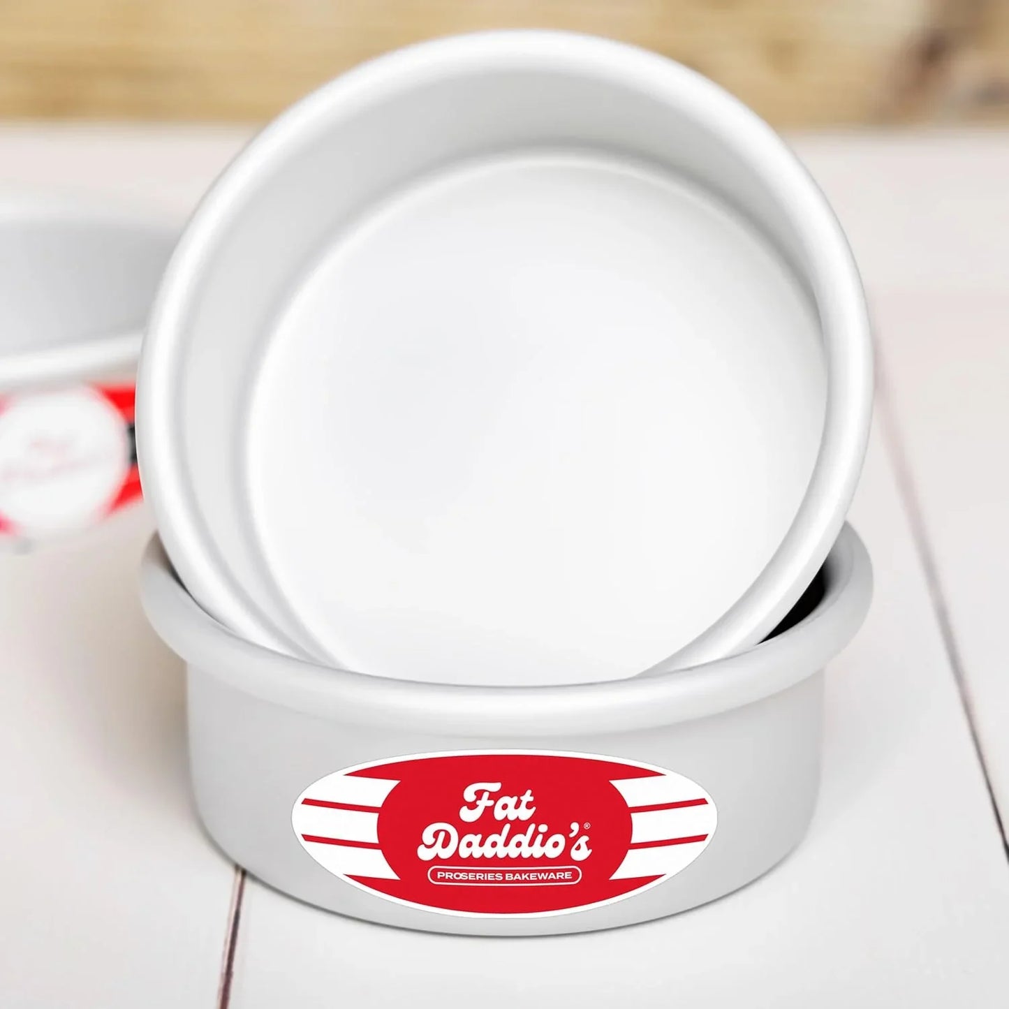 Fat Daddio's anodized aluminum round cake pans set with red label on white wooden surface