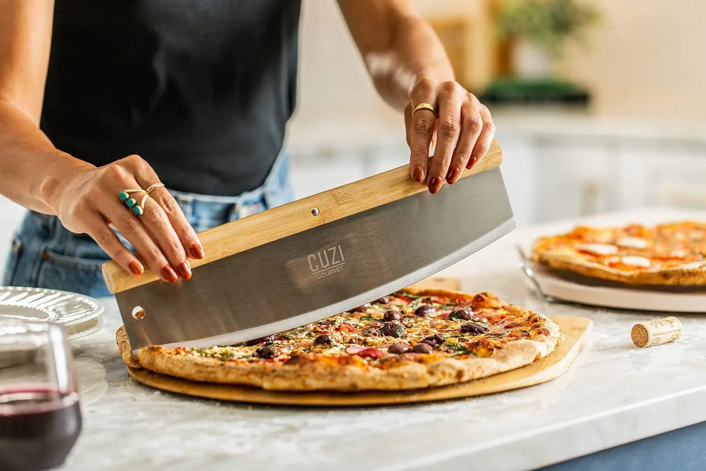 Person slicing thick crust pizza with a bamboo-handled CUZI Gourmet pizza rocker