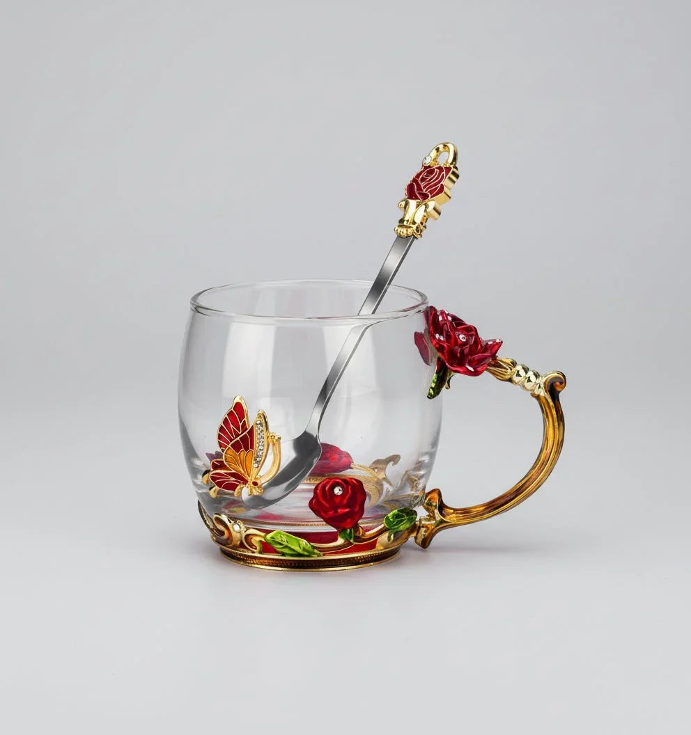 Elegant clear glass coffee mug with ornate red rose and gold butterfly handle, matching spoon