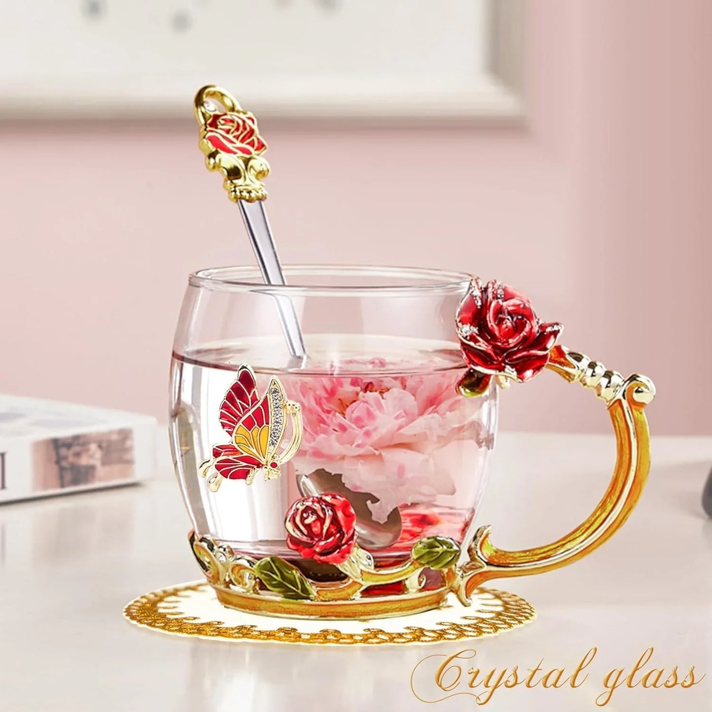 Crystal glass tea cup with red rose and butterfly decorations, filled with pink flower tea
