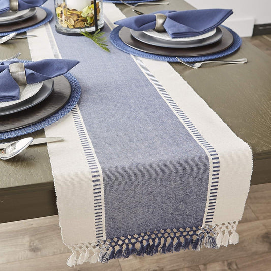 Dining table set with a blue and white table runner, plates, and silverware.