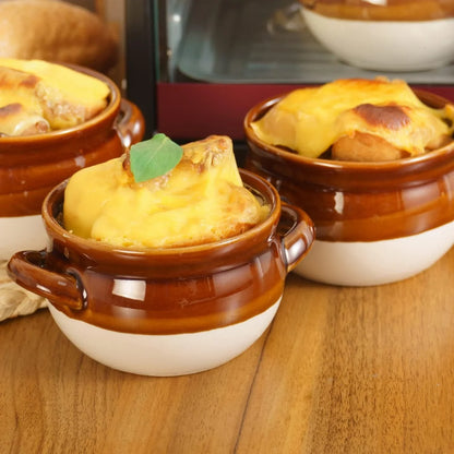 Set of four ceramic brown and white French onion soup bowls with handles on wooden table