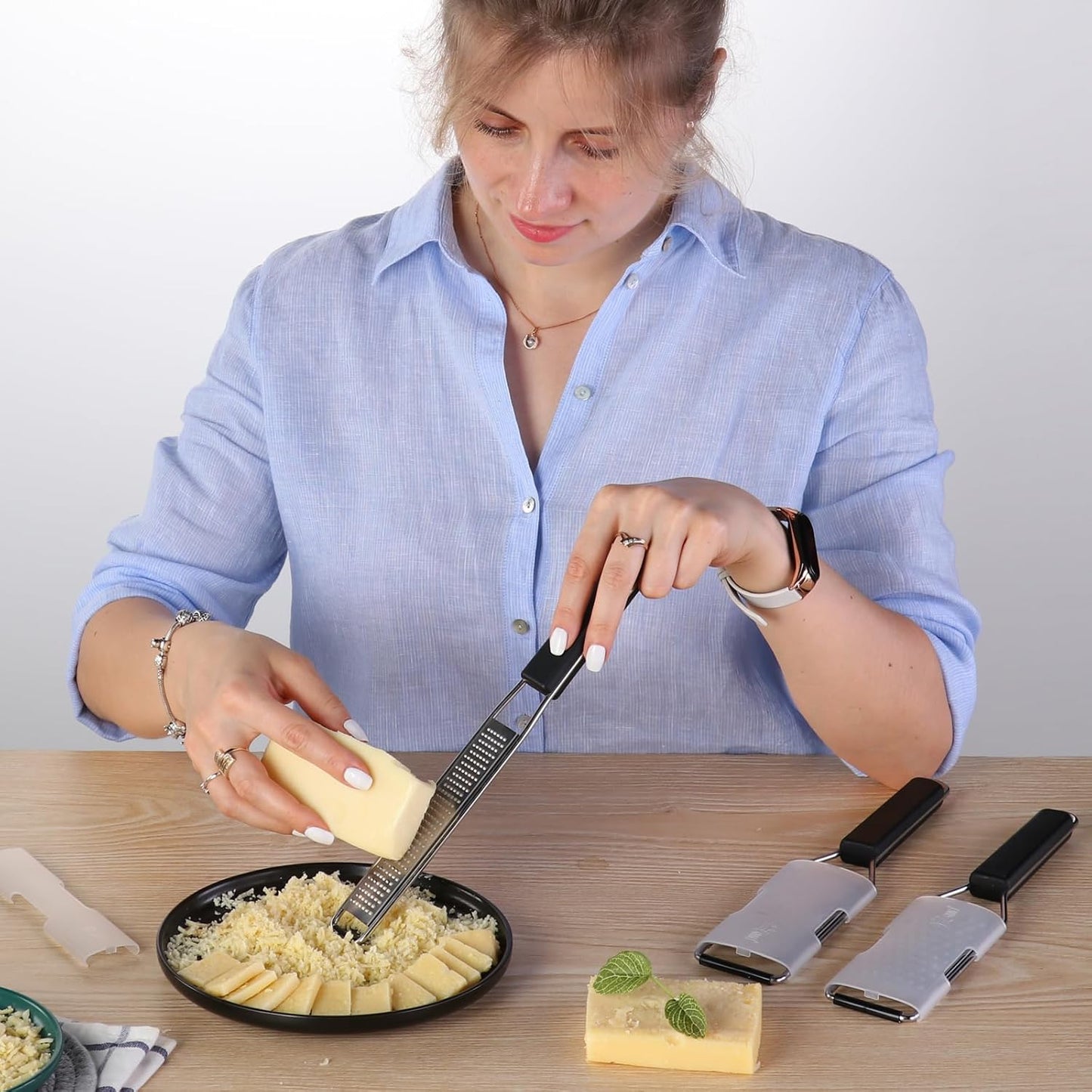 Coarse grater shredding Parmesan cheese over a bowl of pasta.