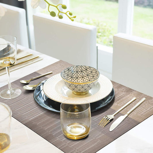 Dining table setting with plates, bowls, glasses, and cutlery on a placemat.