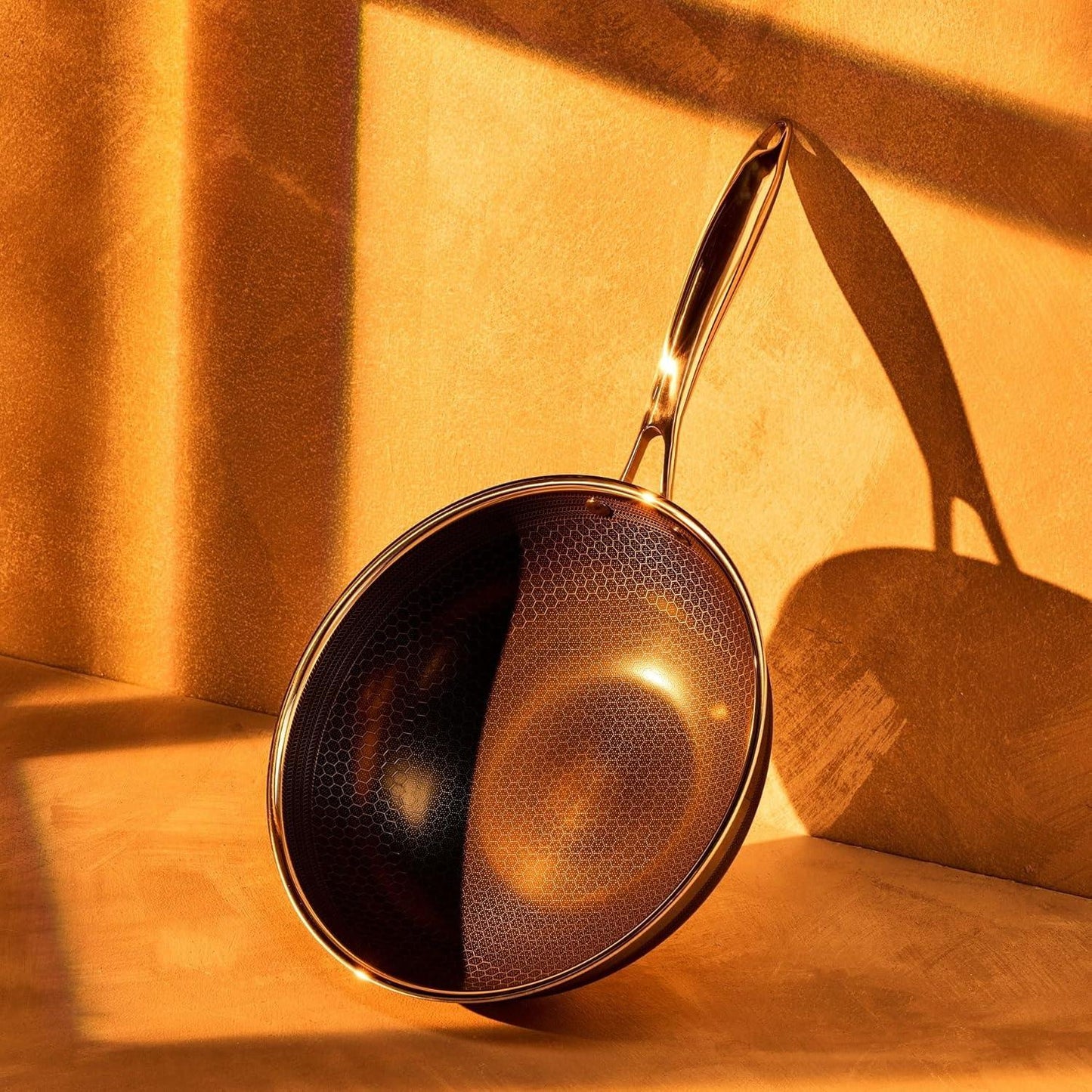 10-inch hybrid nonstick wok pan with honeycomb surface and golden metal handle on orange background