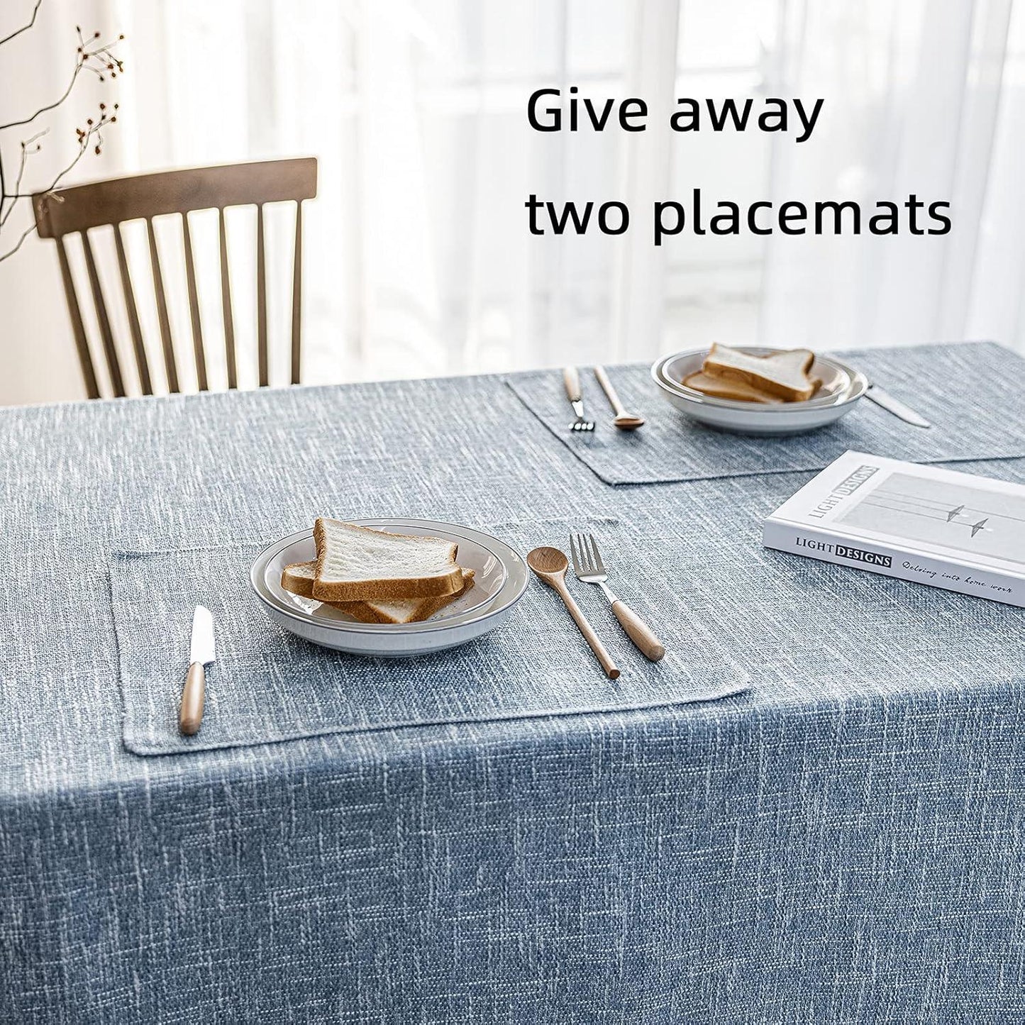 Table setting with placemats, plates, cutlery, and a book on a blue tablecloth.