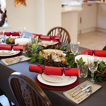 Elegant dining table set with 20-piece gold accent stainless steel flatware, red crackers, and festive greenery