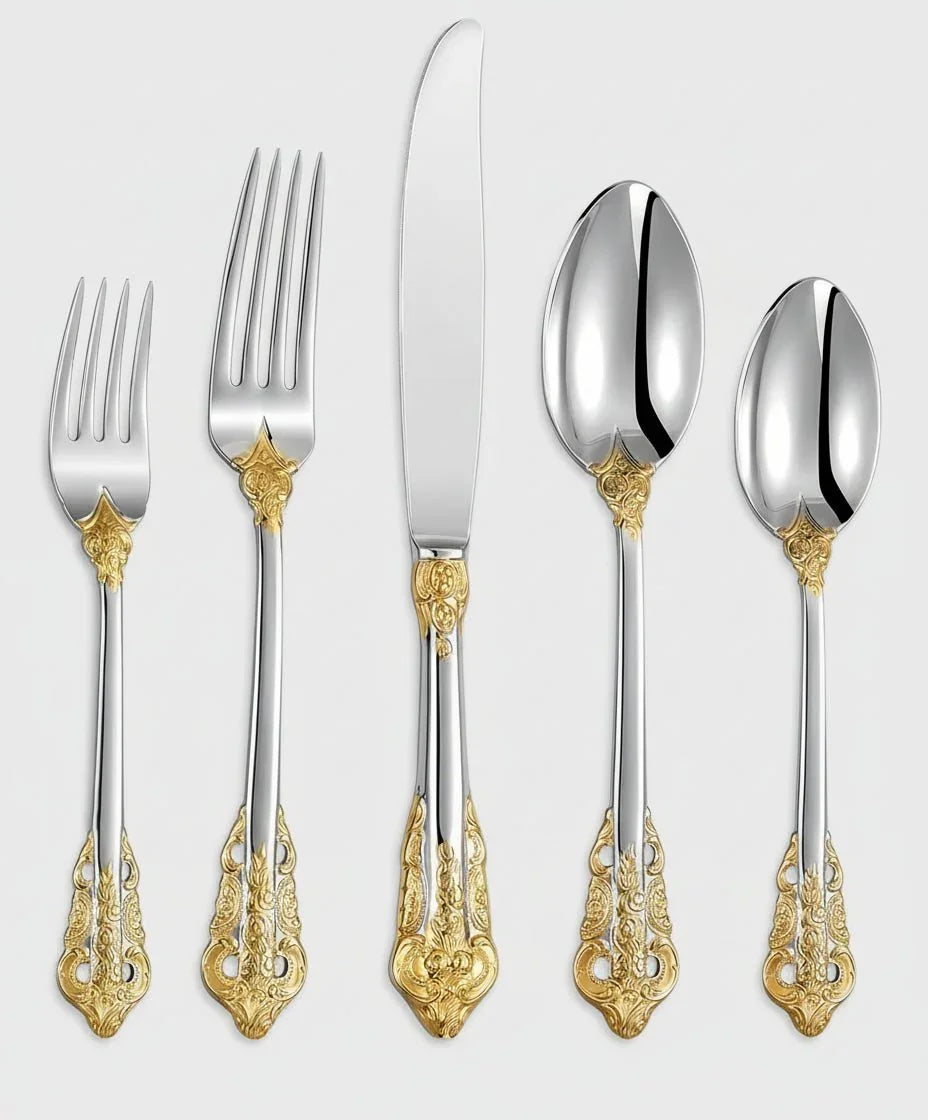 Silver flatware set with intricate gold accents, including forks, knife, and spoons on white background