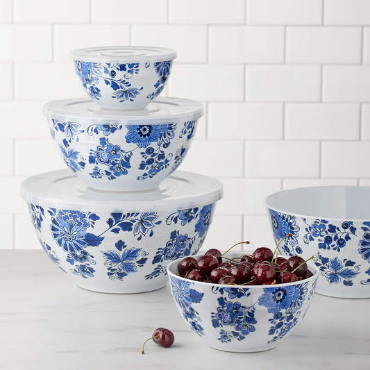 Set of five nesting blue and white floral melamine mixing bowls with lids, one bowl filled with fresh cherries