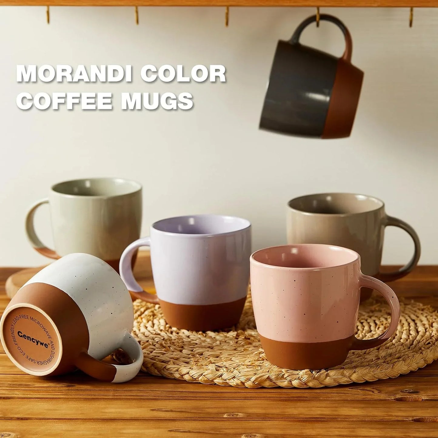 Set of six Morandi color ceramic coffee mugs on wooden table with woven placemat, one hanging