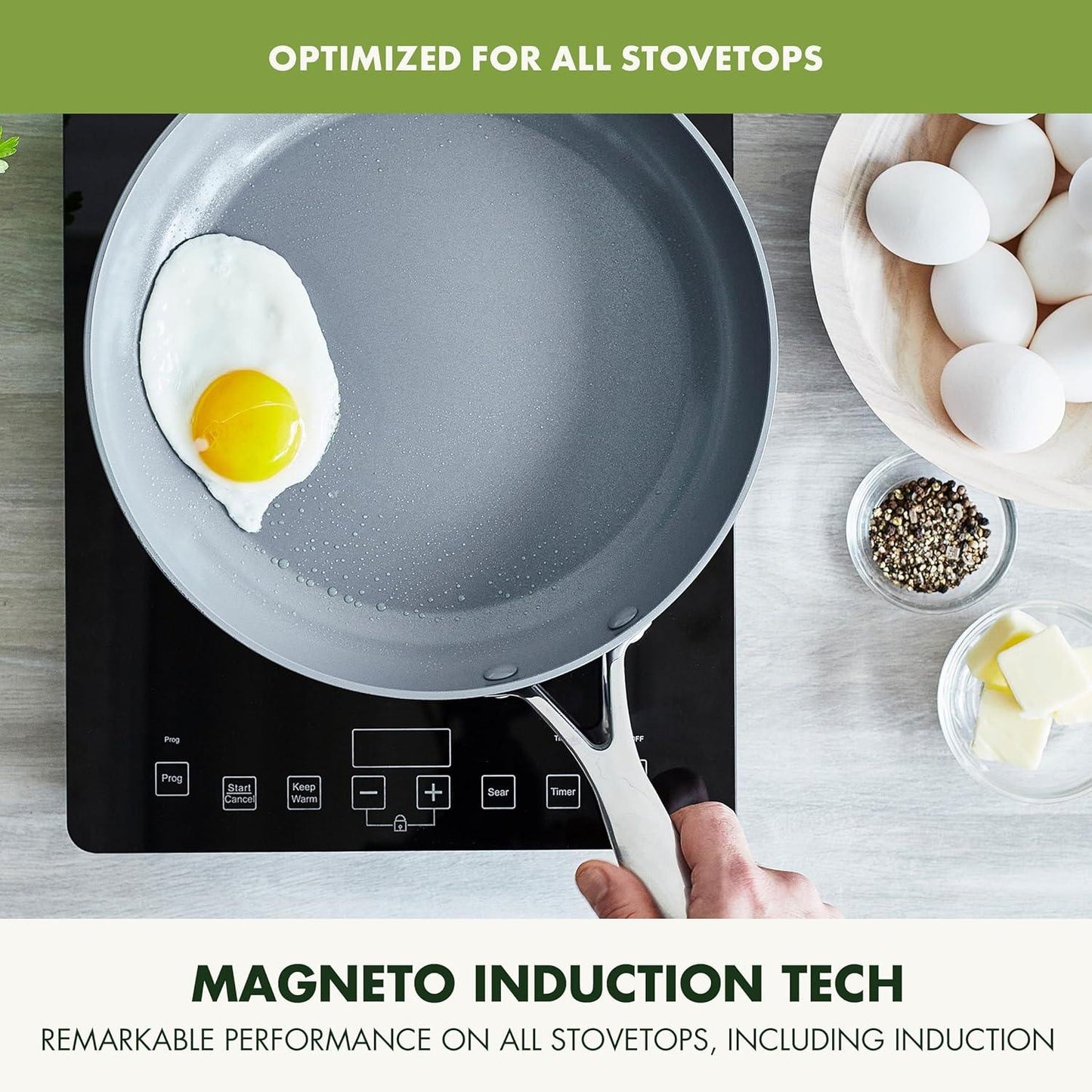 Hand holding pro hard anodized ceramic nonstick frying pan with fried egg on induction stovetop, eggs and butter nearby