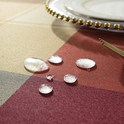 Silver water droplet-shaped objects on a checkered fabric background