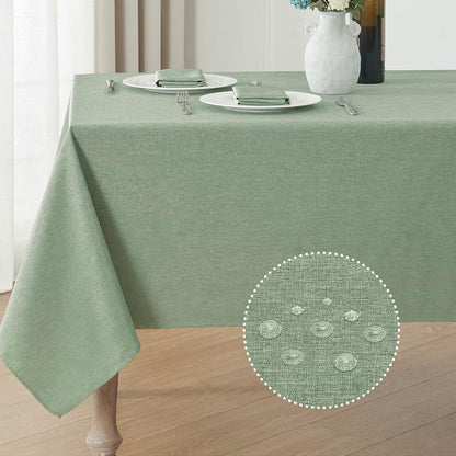 Sage green waterproof linen textured rectangular tablecloth on wooden table with two place settings and floral vase