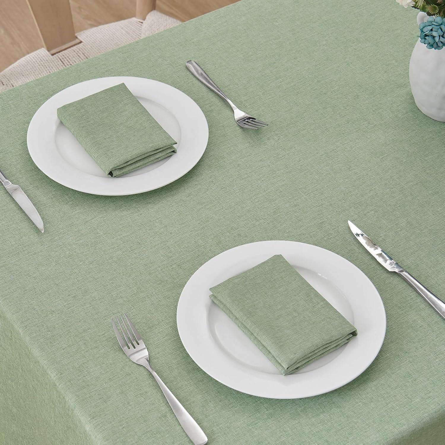 Sage green waterproof linen textured rectangular tablecloth with matching napkins on white plates