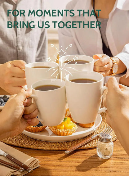 Four people holding white porcelain coffee mugs clinking over a table with pastries and fruit tarts