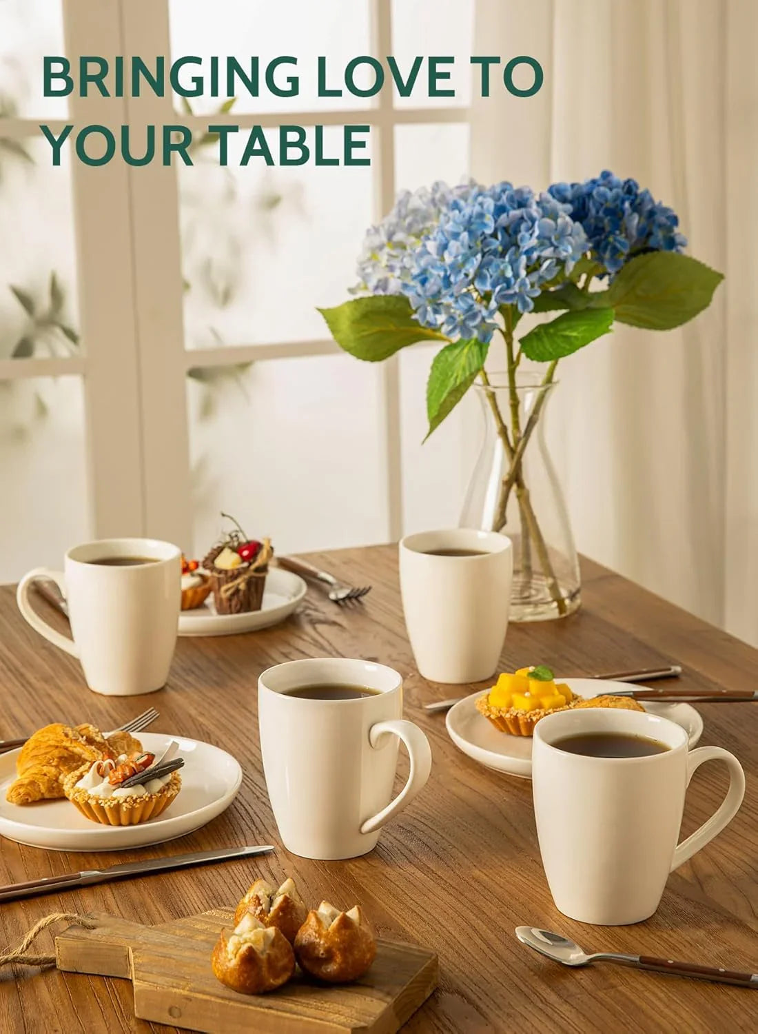 Set of white porcelain coffee mugs filled with coffee on wooden table with pastries and blue hydrangea flowers