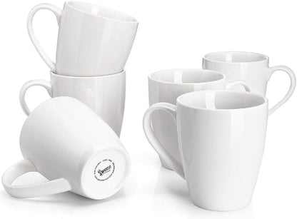 Set of six 16oz white porcelain coffee mugs arranged on a kitchen counter.