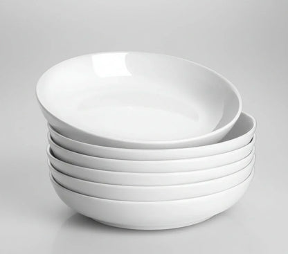 Stack of six white 30oz wide shallow porcelain pasta bowls on gray background