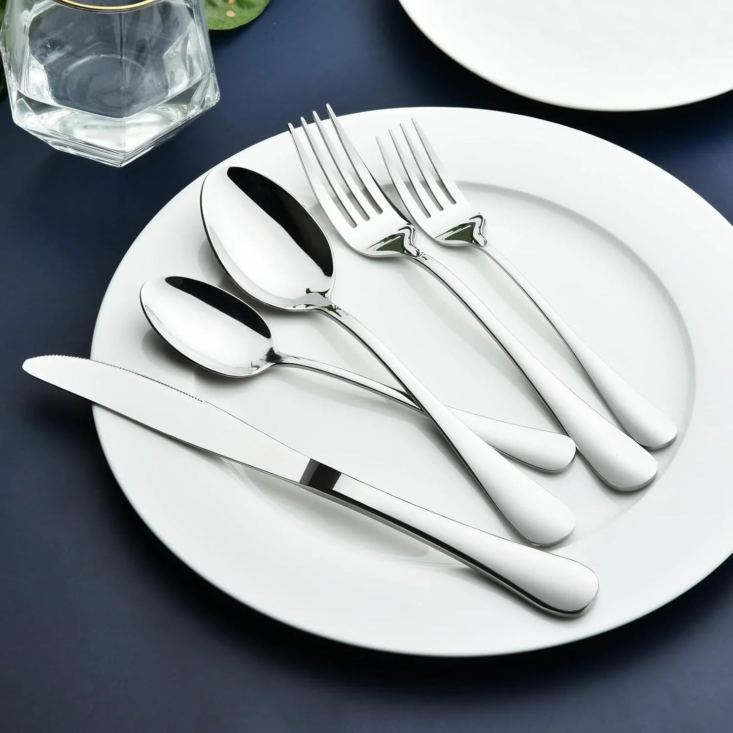 Heavy-duty stainless steel flatware set with forks, spoons, and knife on white plate