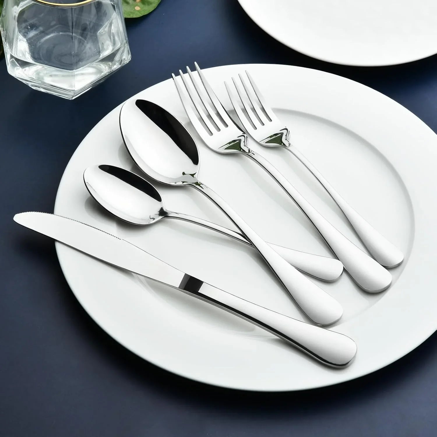 Heavy-duty stainless steel flatware set with forks, spoons, and knife on white plate
