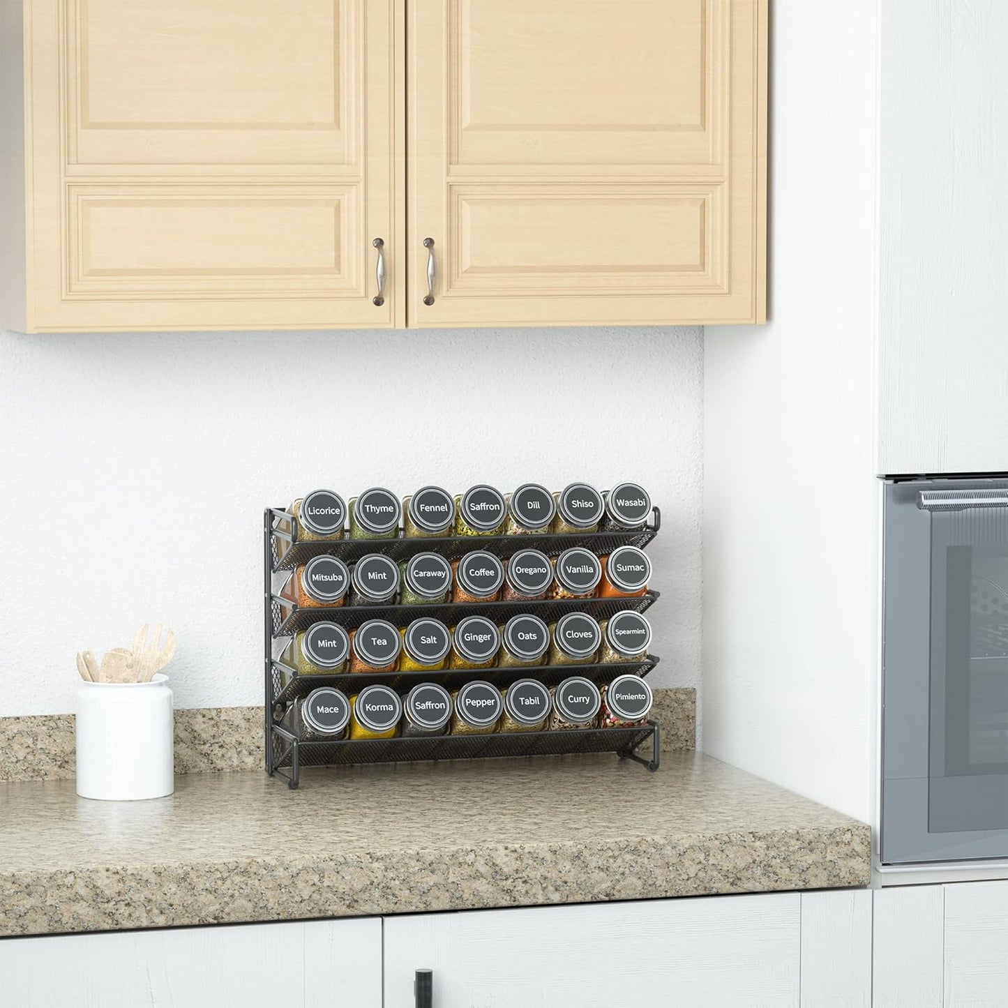 Spice rack set with labeled glass jars on kitchen countertop at Simmerly Home.