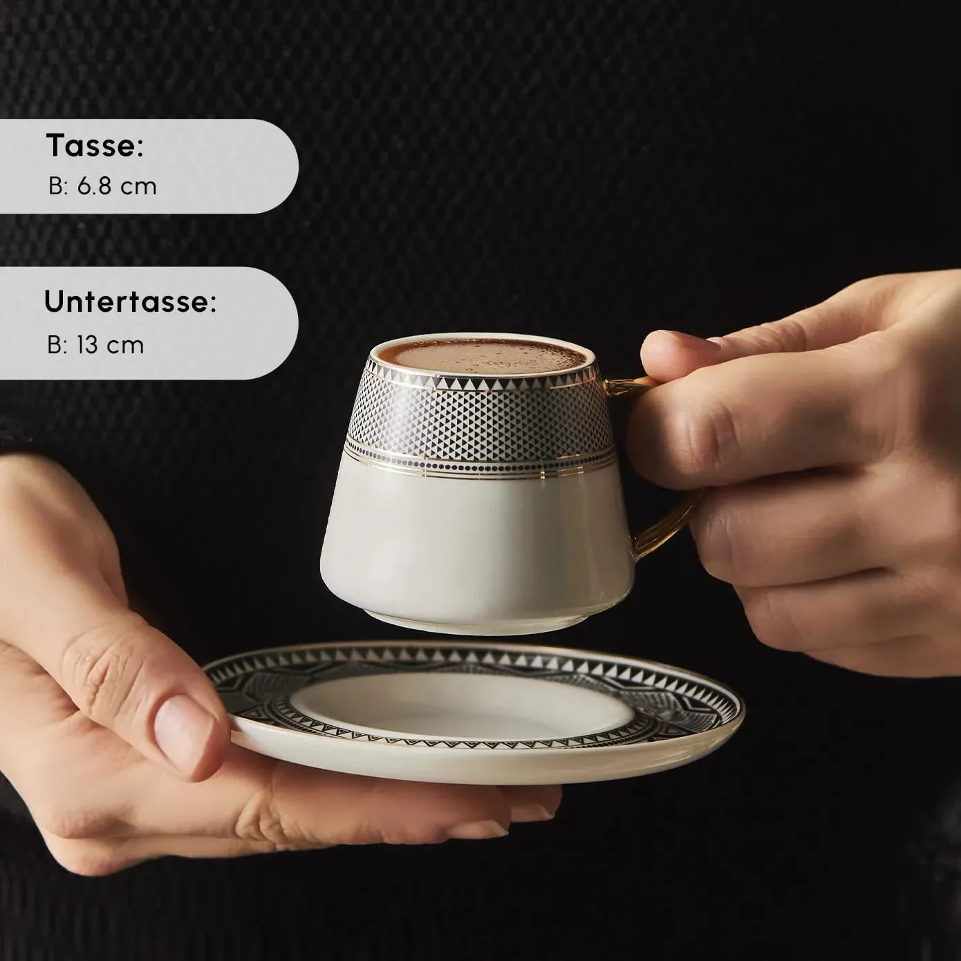 Hand holding a porcelain Turkish coffee cup with geometric pattern and matching saucer on black background