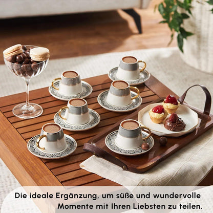 Set of six porcelain Turkish coffee cups with gold handles and patterned saucers on wooden table with desserts and chocolates