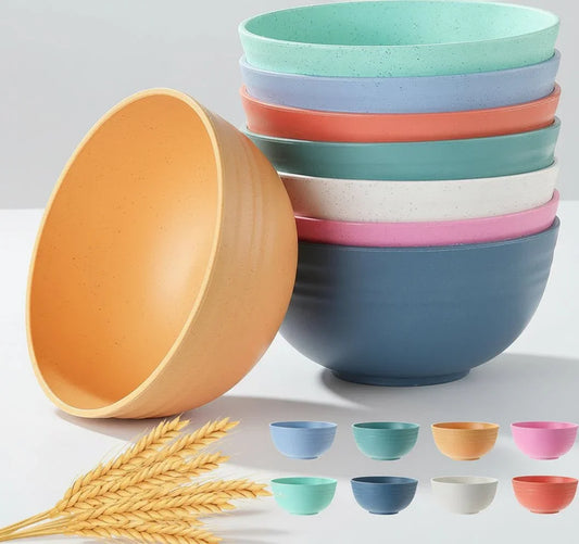 Set of eight colorful unbreakable wheat straw cereal bowls stacked on white surface with wheat stalks