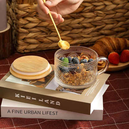 Vintage embossed glass coffee mug with bamboo lid and golden spoon, filled with granola and blueberries on books
