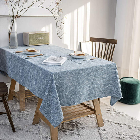 Dining room with a table covered by a blue tablecloth, chairs, and decor items.
